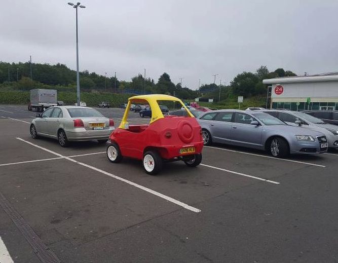 a small red car parked in a parking lot