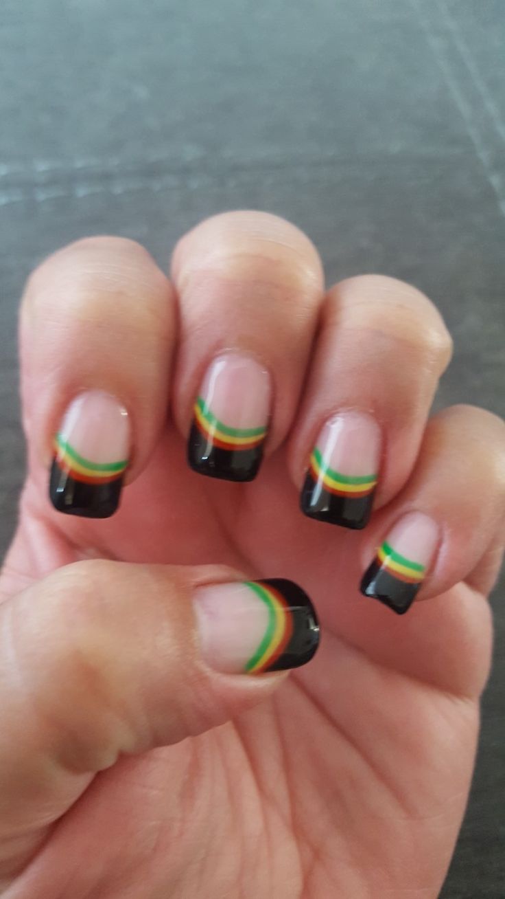 a person with black and green nail polish holding up their fingers to show off the design