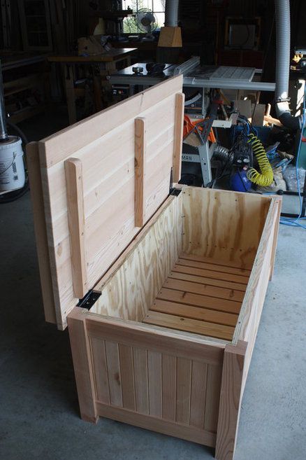 an open wooden box sitting on top of a floor in a room filled with tools