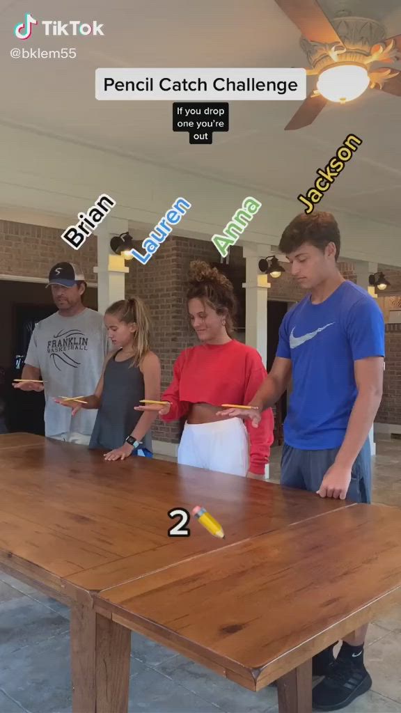 This may contain: a group of people standing around a wooden table with numbers on it and the words pencil catch challenge