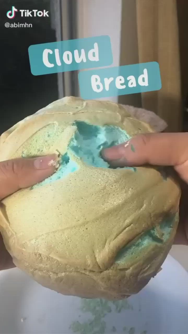 This may contain: a person holding a doughnut with blue icing on it and the words cloud bread