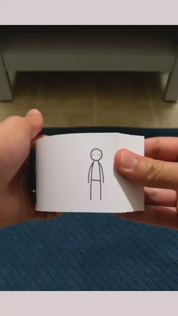 This may contain: a person holding a piece of paper with a stick figure on it