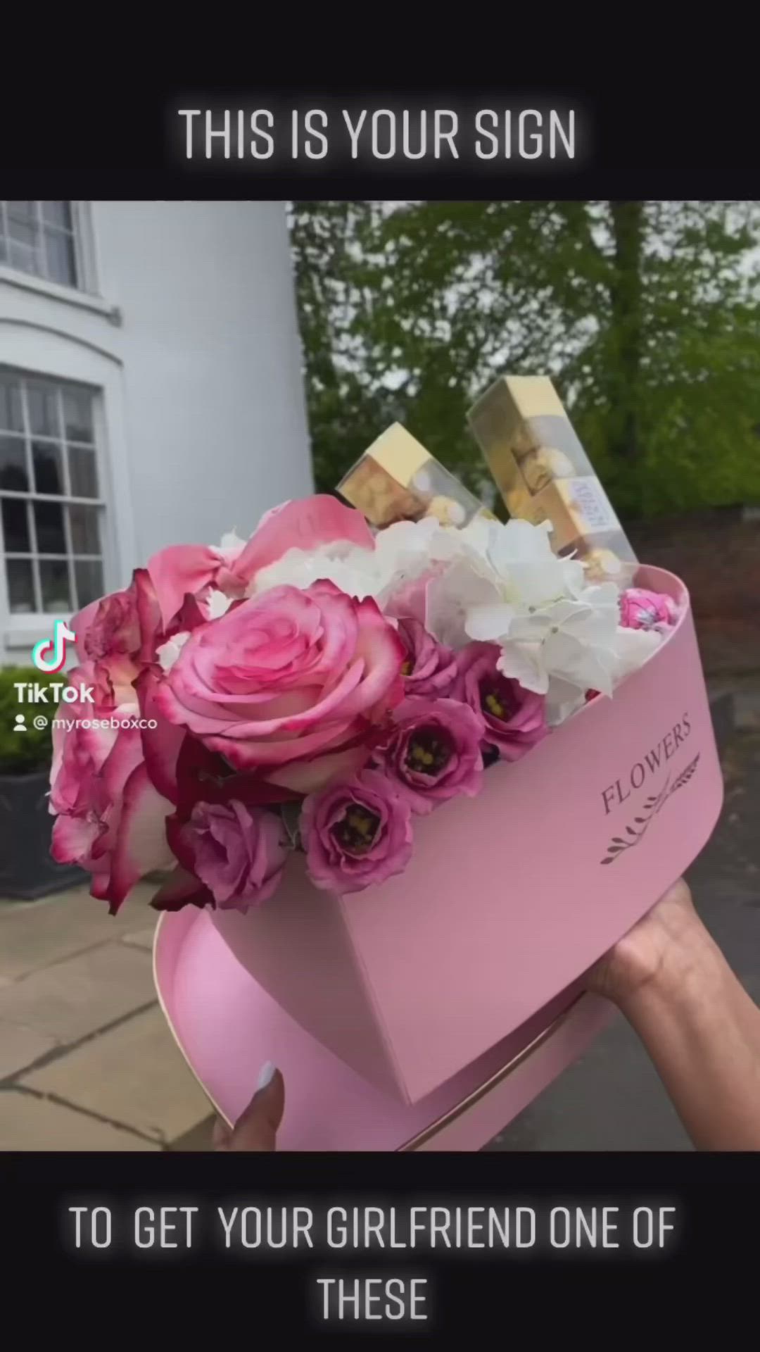 This may contain: someone is holding a pink box with flowers in it that says, this is your sign to get your girlfriend one of these