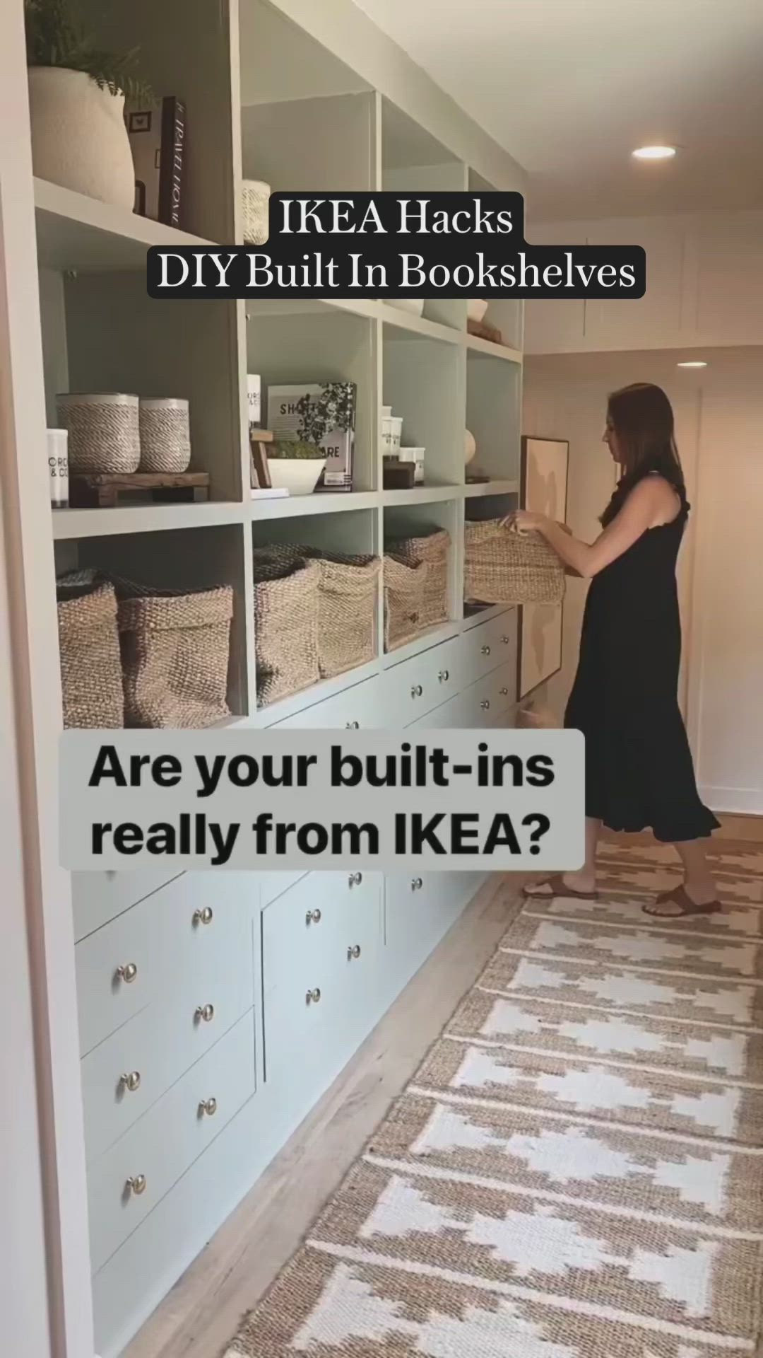 This may contain: a woman standing in front of a white book shelf filled with books and other items