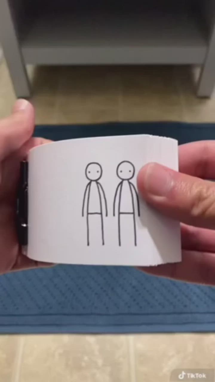 This may contain: a person holding a piece of paper with stick figures on it in front of a toilet