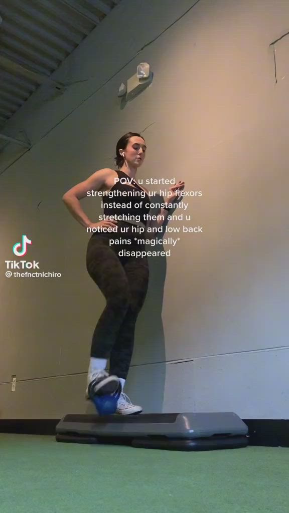 This may contain: a woman standing on top of a black mat in front of a wall with words above her