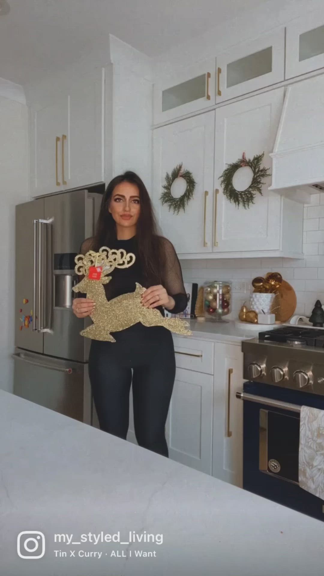 This may contain: a woman is holding a gold christmas decoration