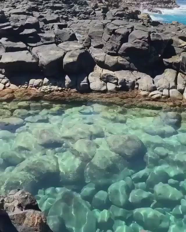 This may contain: the water is very clear and blue with some rocks around it, as seen from above