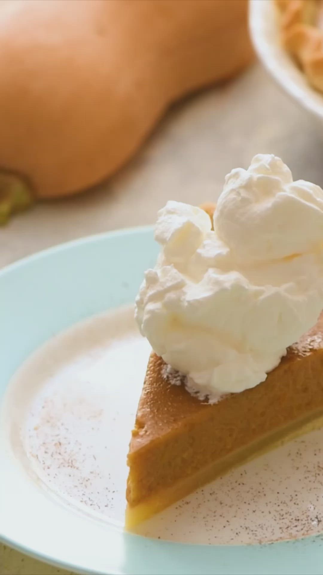 This may contain: a slice of pumpkin pie with whipped cream on top is sitting on a blue plate