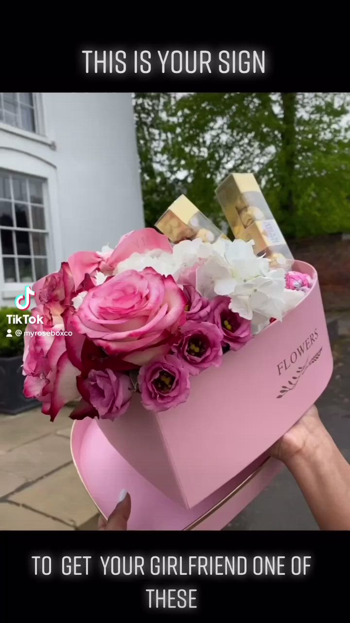 This may contain: someone is holding a pink box with flowers in it that says, this is your sign to get your girlfriend one of these