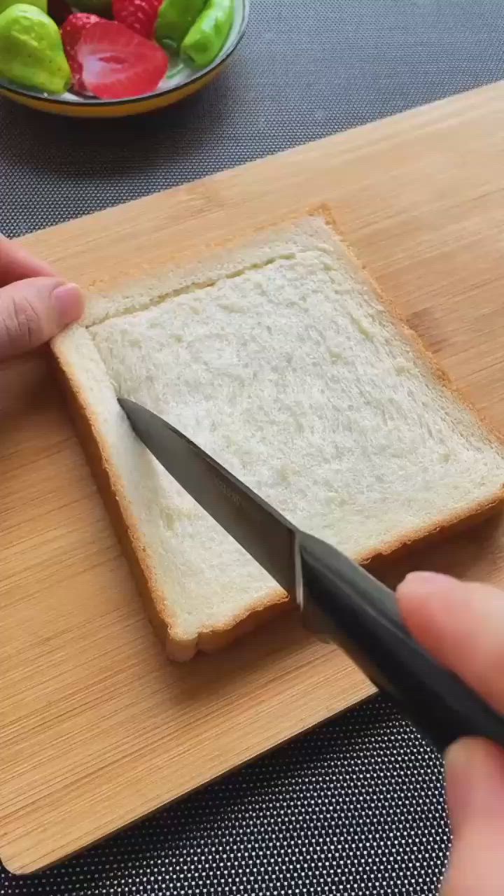 This may contain: a person cutting bread with a knife on a cutting board