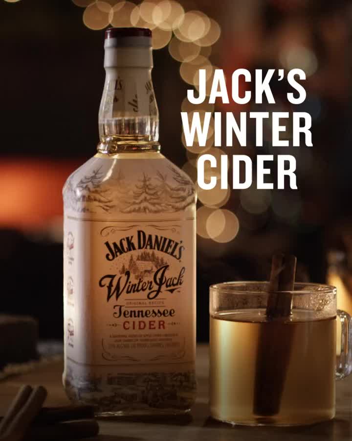 This may contain: a bottle of jack's winter cider next to a glass with cinnamon sticks