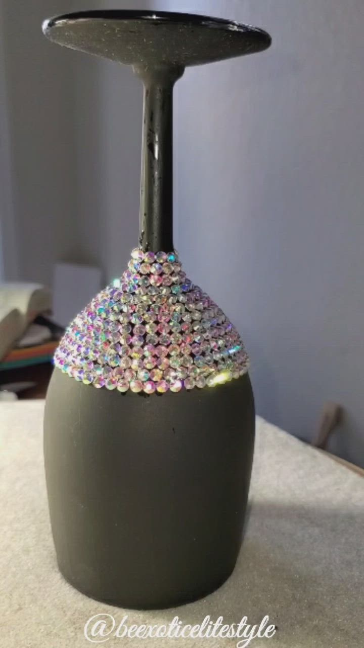 This may contain: a black vase with silver and multicolored beads on it sitting on a table