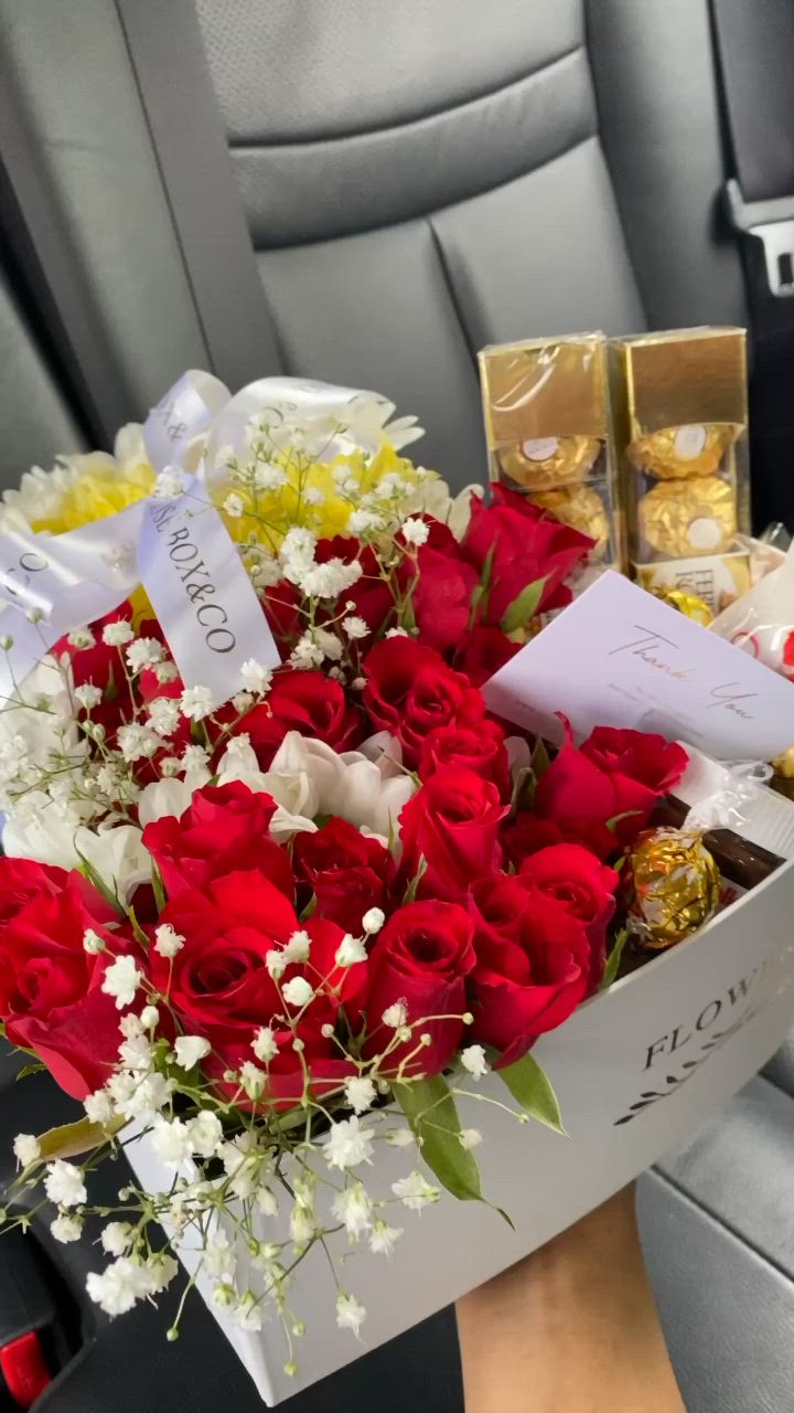 This may contain: a bouquet of roses and chocolates in a car