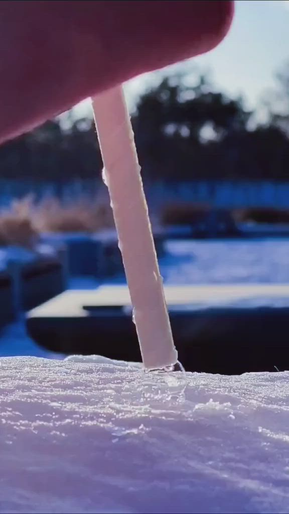 This may contain: a person holding a toothbrush in their hand while standing next to snow covered ground