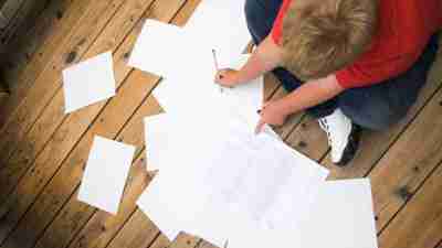 Boy working on his homework while sitting on the floor, using executive functions