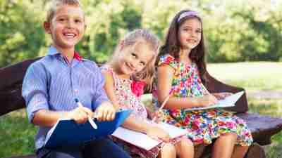 Three children avoid summer learning loss by reading together on a bench
