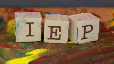 Three blocks spelling "IEP" on paint covered table, which is important to know about if a child has ADHD