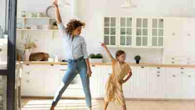 A mother and her daughter dancing to music in the kitchen