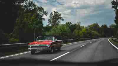 A classic red car on the road. Road trip safety tips.