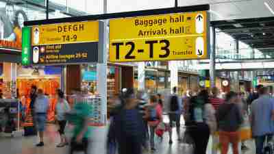 People Walking Beside Baggage Hall and Arrivals Hall Signage at an airport