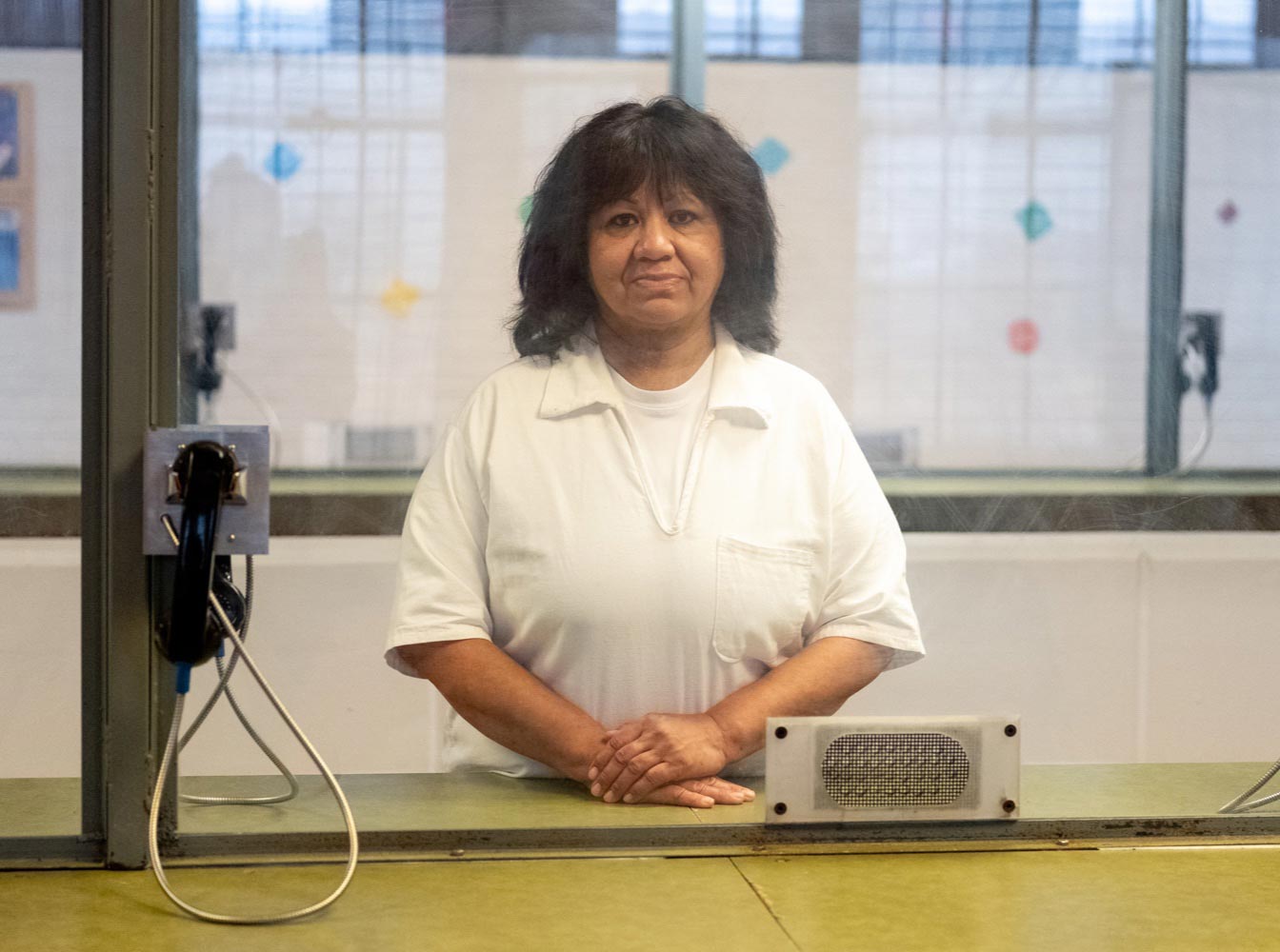 Melissa Lucio poses for a portrait behind glass at the Mountain View Unit in Gatesville, Texas. (Image: Ilana Panich-Linsman for The Innocence Project)