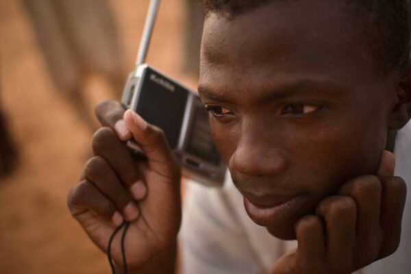 A man holds a portable radio up to his ear