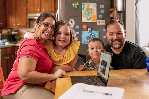 A family of four sitting at a kitchen table smiling