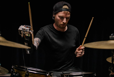 A person in a backwards hat plays the drums.