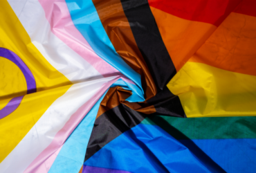 Photo of an intersex-inclusive progress pride flag swirled as it lays on a flat surface.