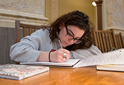 female student writing notes at a desk