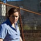 Actress/Director Jillian Armenate leans against the prison yard fence for Kittens in a Cage.