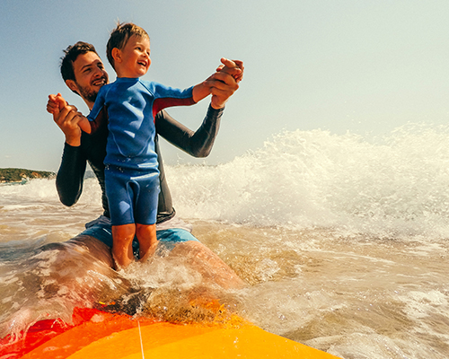 a man and a boy riding a surfboard