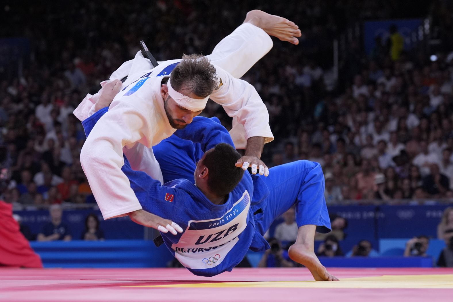 Azerbaijan's Zelym Kotsoiev, top, and Uzbekistan's Muzaffarbek Turoboyev compete in a judo semifinal on August 1. <a href="https://www.cnn.com/sport/live-news/paris-olympics-news-2024-08-01-24#h_64b2fa86bf716965285544ea96743ae2"