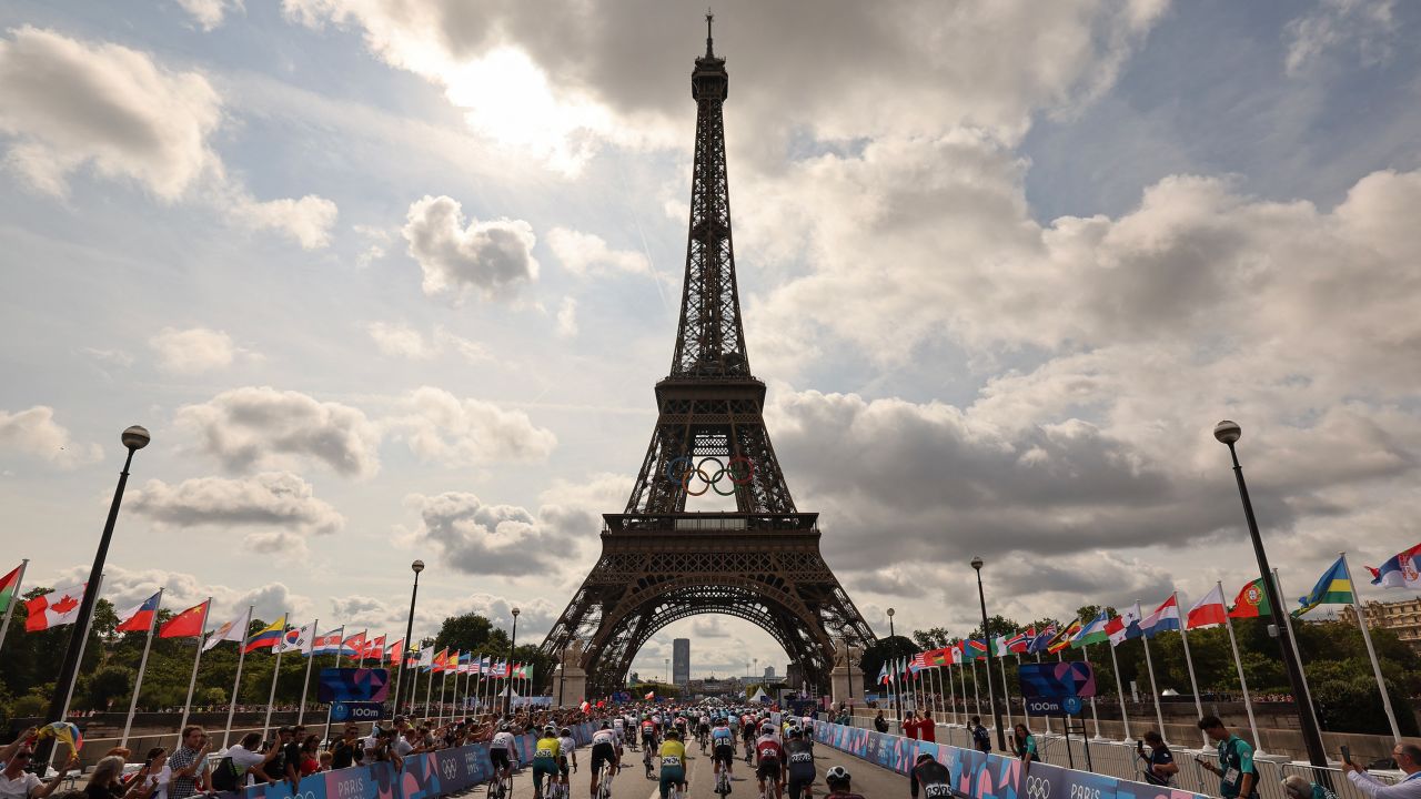 The pack of riders (peloton) cycles at the foot of the Eiffel Tower at the start of the men's cycling road race during the Paris 2024 Olympic Games in Paris, on August 3, 2024.