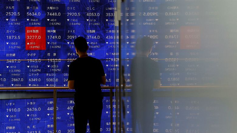 A man stands next to an electronic stock quotation board inside a building in Tokyo, Japan August 2, 2024. REUTERS/Issei Kato