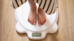 a little girl in a dress is standing on white scales that show her weight, 3 years