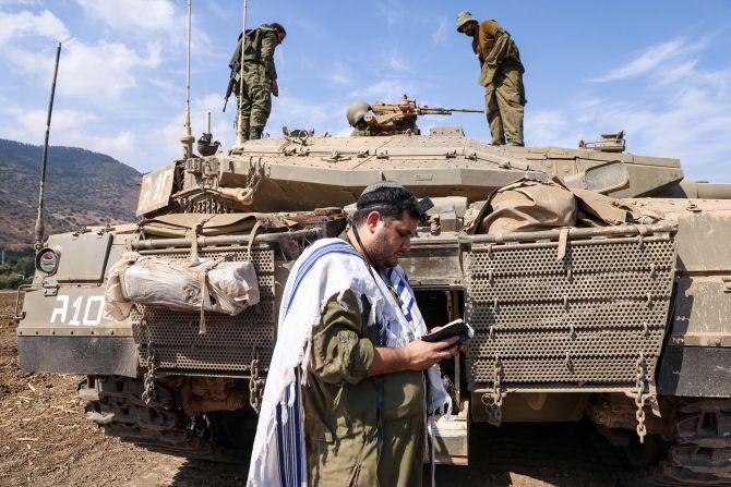 An Israeli soldier prays standing in front of a tank on the outskirts of the northern town of Kiryat Shmona on October 8.