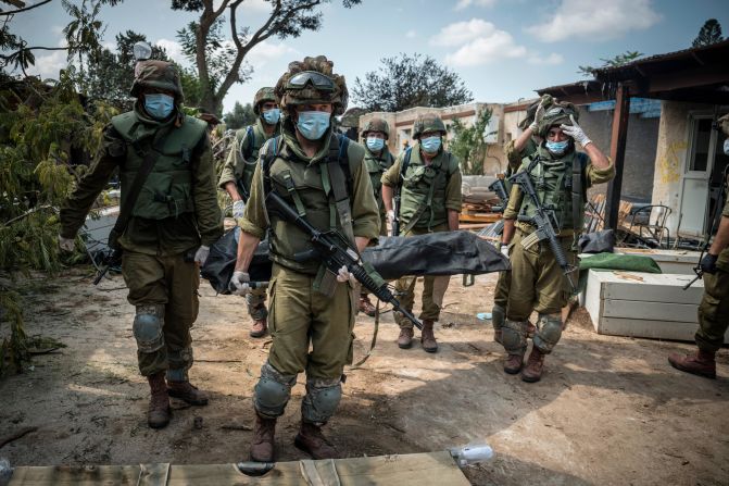 Israeli soldiers carry a body on October 10 in Kfar Aza, a village in Israel just across the border from Gaza. Hamas militants carried out a "massacre" in Kfar Aza during their attacks over the weekend, <a href="https://www.cnn.com/middleeast/live-news/israel-hamas-war-gaza-10-10-23/h_7867b7563e54a0b29dddeada7e4c2722" target="_blank"