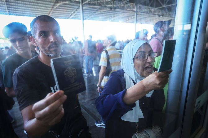 Palestinians with dual citizenship show their passports while seeking permission to leave Gaza at the Rafah border crossing into Egypt, on November 1.