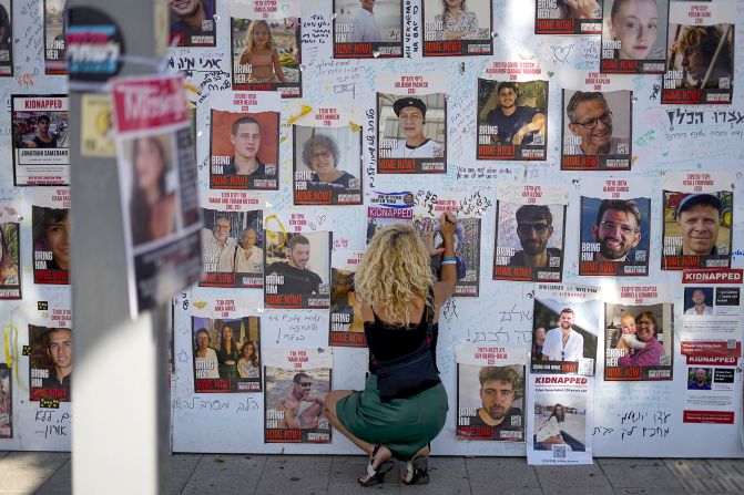 A woman in Tel Aviv writes on a photo of people kidnapped during the October 7 Hamas attack in Israel.