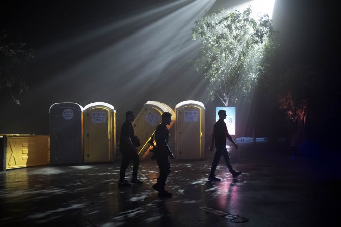 Security guards and a member of Israeli security forces pass a display of toppled toilets during a press tour of the 06:29 memorial recreating the site of the Nova music festival massacre in Tel Aviv, Israel, on December 6.