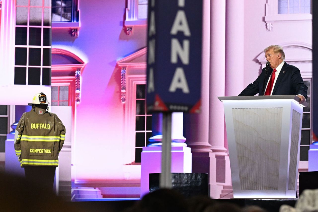 Former President Donald Trump on stage with a firefighter uniform, representing Cory Comperatore, the firefighter who was killed during the rally where an assassination attempt was made on Trump's life. 