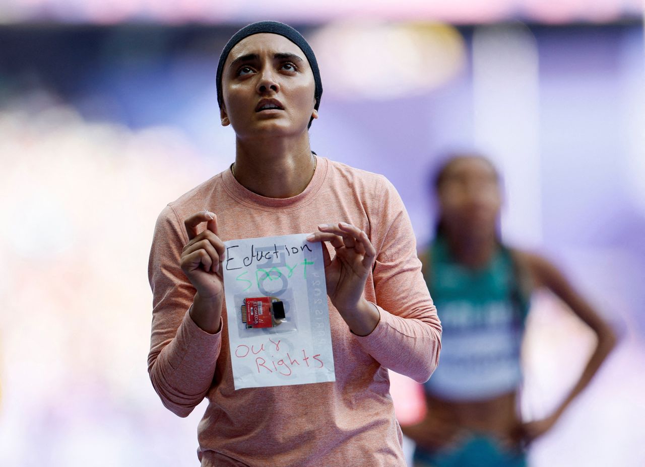 Kimia Yousofi of Afghanistan holds up a sign after competing in the women's 100m preliminary round in the Stade de France in Saint-Denis, France, on August 2.