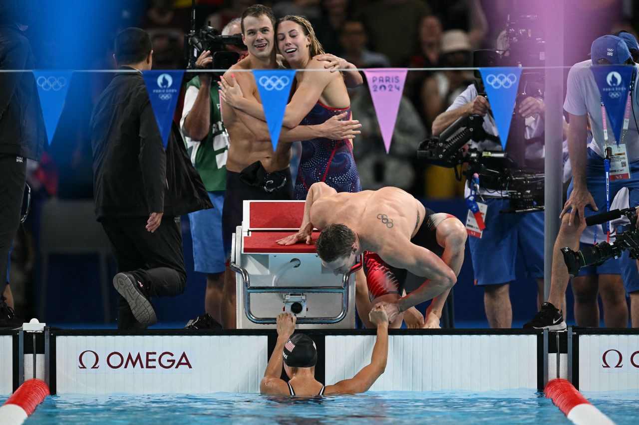 Gretchen Walsh and Nic Fink embrace as Ryan Murphy congratulates Torri Huske after the team won the mixed 4x100-meter medley relay final Saturday. 