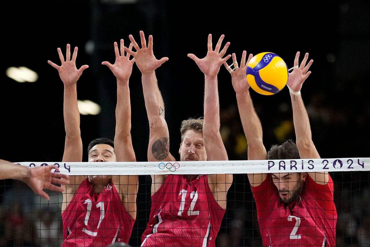 Micah Christenson, Maxwell Holt, and Aaron Russell, of the United States, block a ball during a men's quarter final volleyball match between the United States and Brazil.