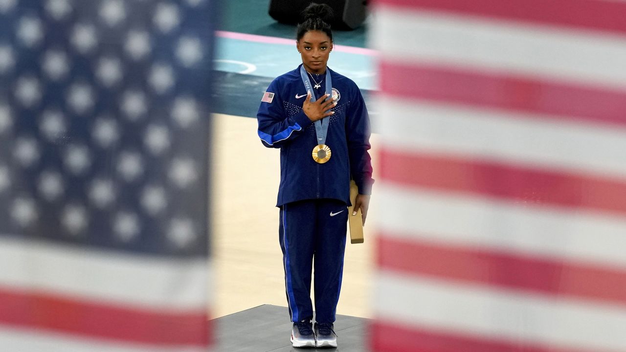 Simone Biles pauses for the United States national anthem after winning the gold medal during the women's artistic gymnastics all-around finals in the Bercy Arena in Paris today.