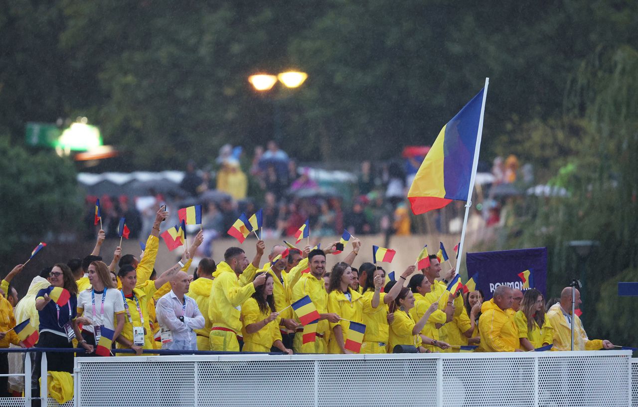 Ionela Livia Cozmiuc and Marius Vasile Cozmiuc, flagbearers for Team Romania, wave the flag along the River Seine.