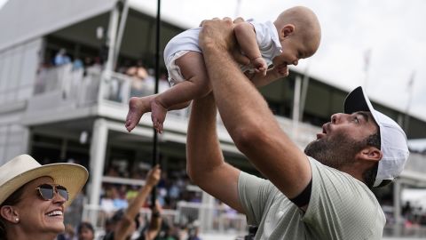 Scottie Scheffler holds his son Bennett Ezra Scheffler as his wife Meredith Scudder looks on the 18th green after Scheffler won the final round of the Tour Championship golf tournament, Sunday, Sept. 1, 2024, in Atlanta. (AP Photo/Mike Stewart)