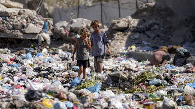 Displaced kids sort through trash at a street in Deir al-Balah, central Gaza Strip, Thursday, Aug. 29, 2024. (AP Photo/Abdel Kareem Hana)